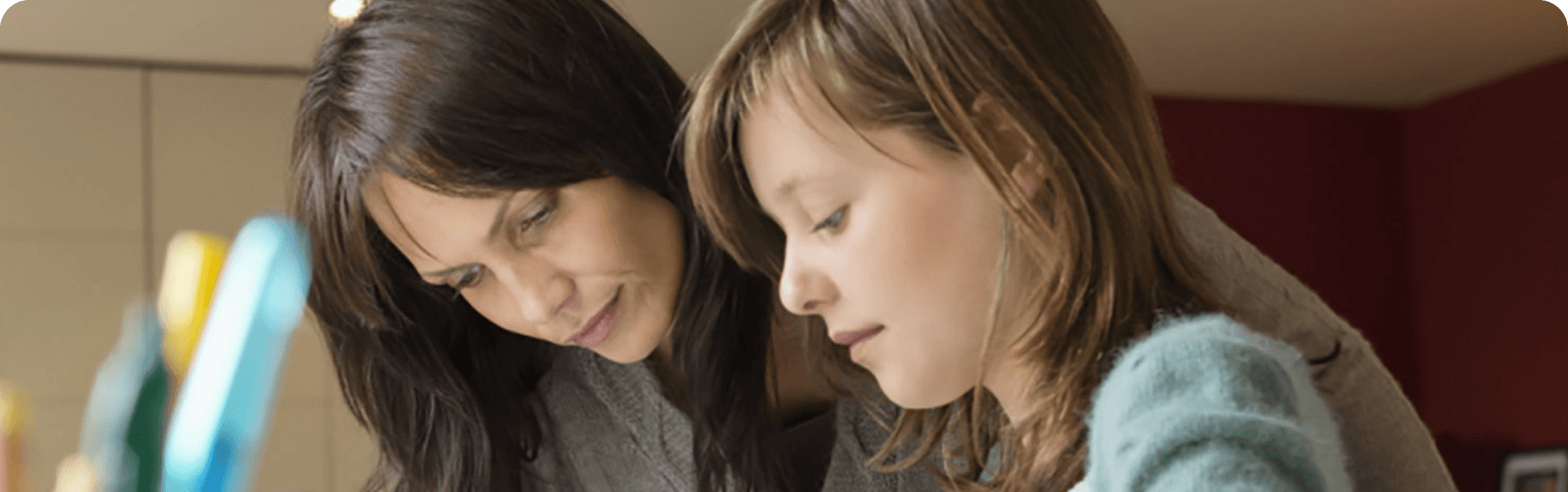 Photograph of a woman and a young girl studying at a desk